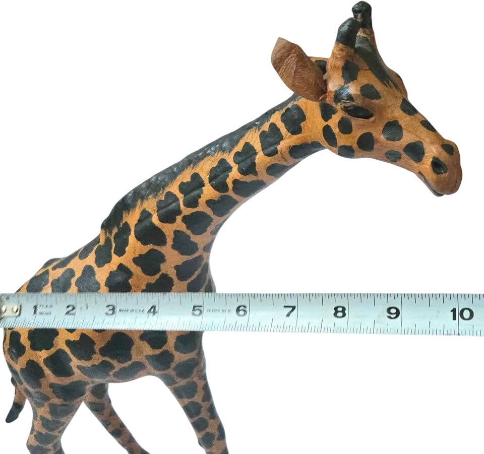 Giraffe figurine next to a ruler on a white background